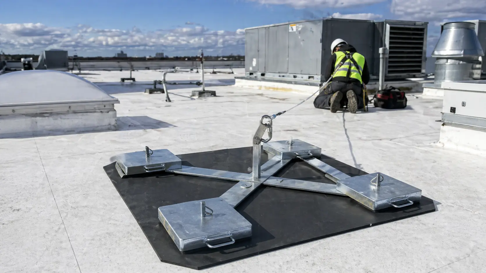Worker securing rooftop fall protection system